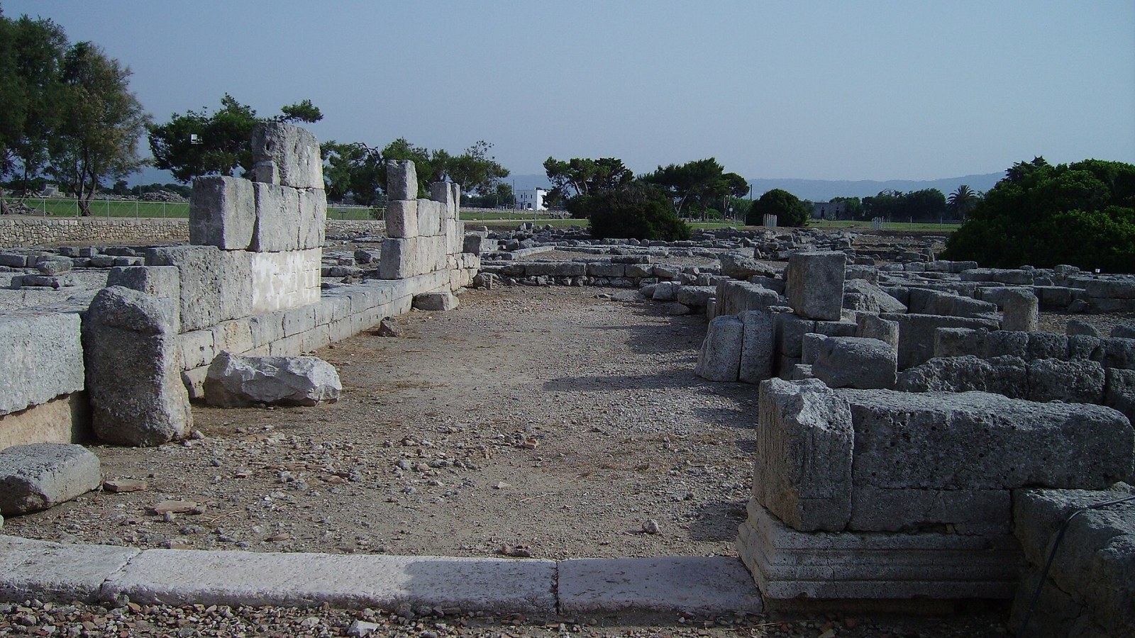 I resti della via Traiana che attraversa il parco archeologico di Egnazia, con le mura messapiche sullo sfondo e il mare Adriatico all'orizzonte