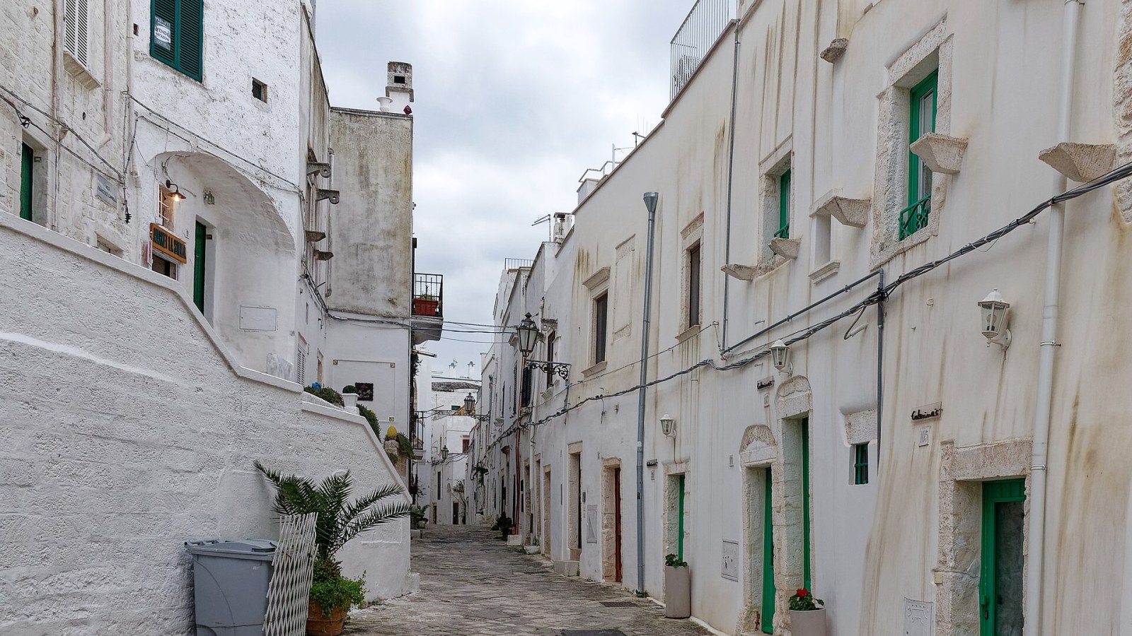 Le mura angioino-aragonesi di Ostuni viste dall'alto al tramonto, con Porta Nova in primo piano e il centro storico sullo sfondo