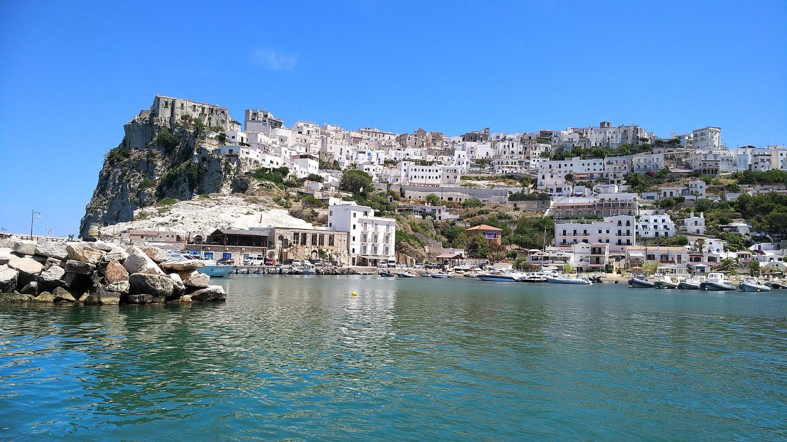 Il borgo bianco di Peschici visto dall'alto, con le scalinate nella roccia che scendono verso il mare adriatico al tramonto