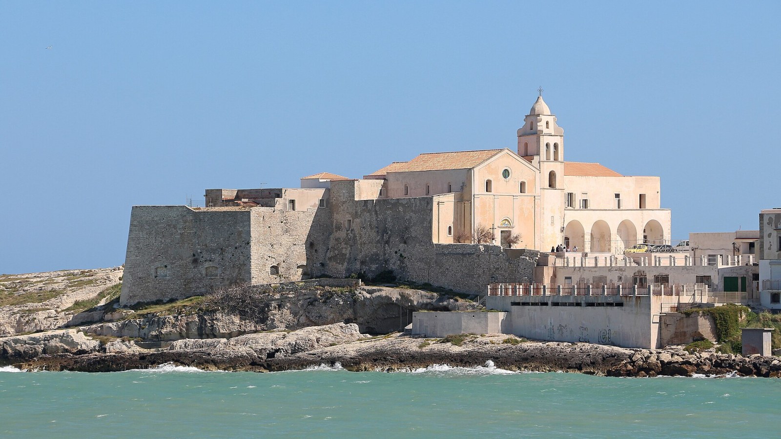 Il promontorio di Vieste visto dall'alto, con il centro storico bianco che si protende sul mare Adriatico al tramonto
