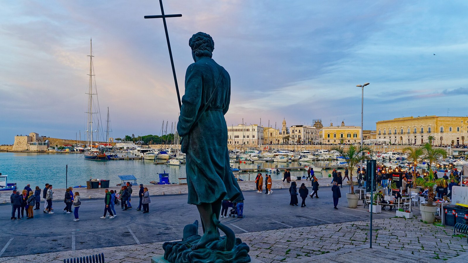 La cattedrale romanica di Trani vista dal mare al tramonto, con la facciata in pietra calcarea rosata e il campanile che si staglia sul cielo adriatico