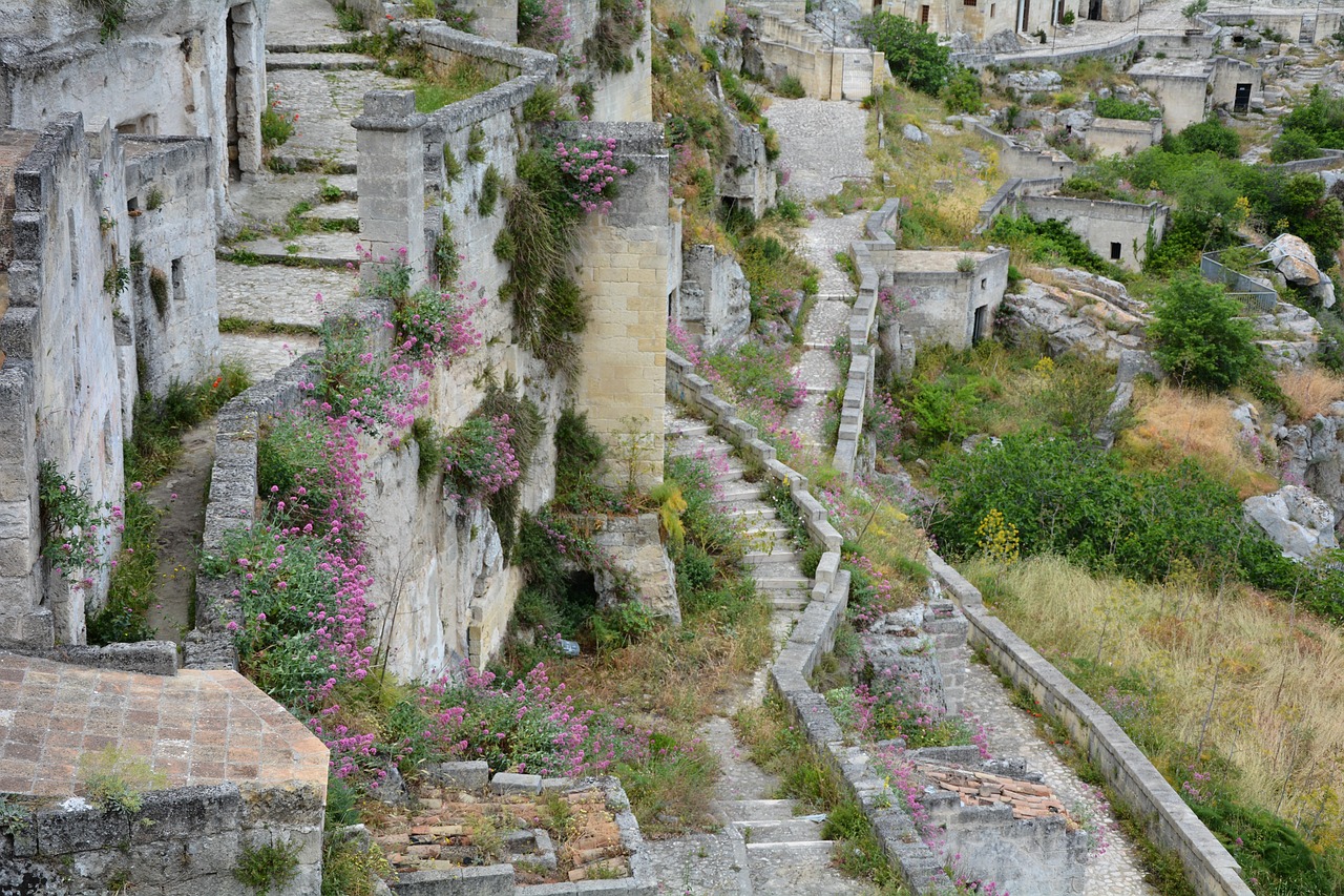 Panorama dei Sassi di Matera in primavera, con fiori colorati e cielo blu.